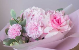 Soft pink floral bouquet with roses and carnations wrapped in pastel paper